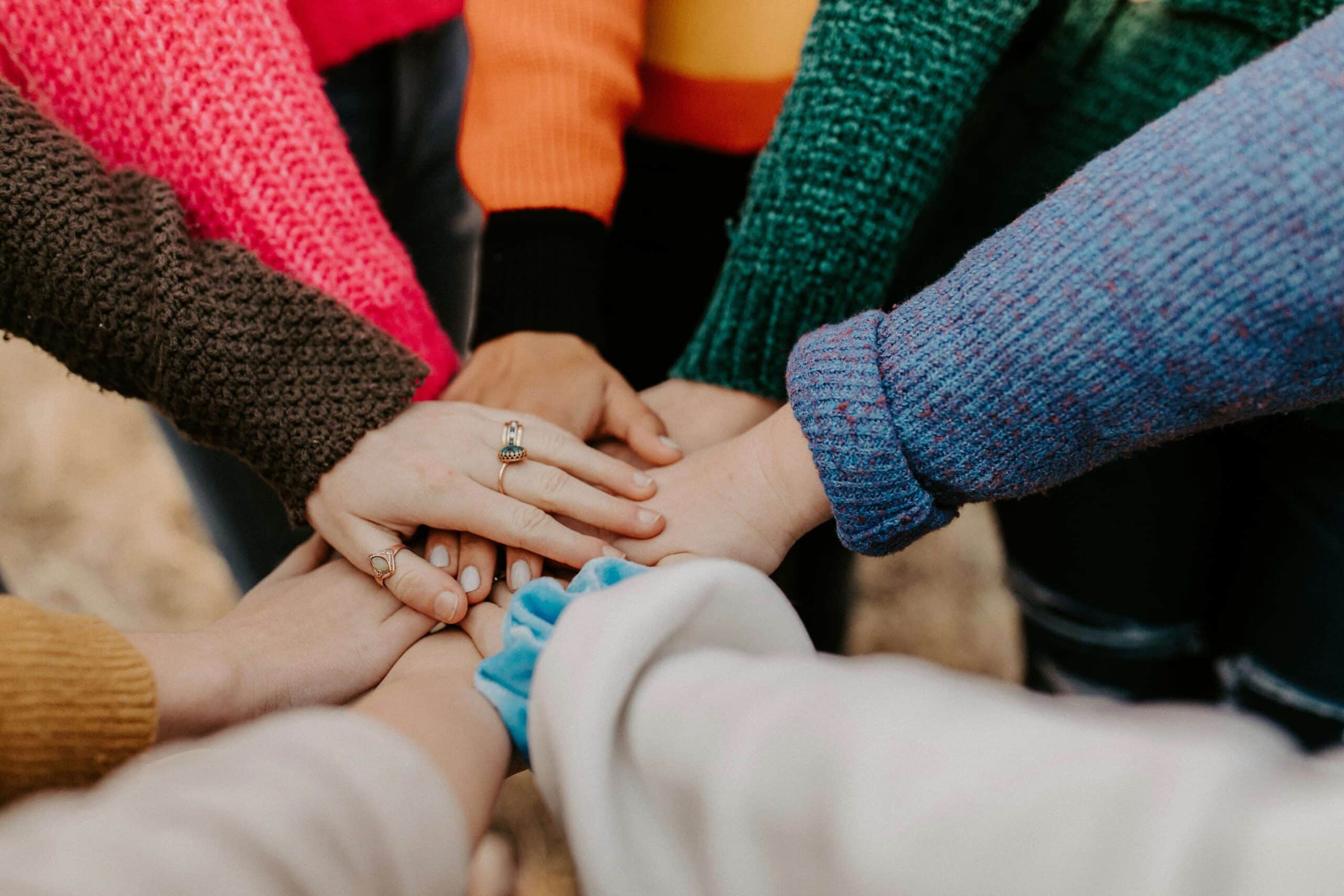 A group of people putting their hands together in a circle | Gender Pay Gap